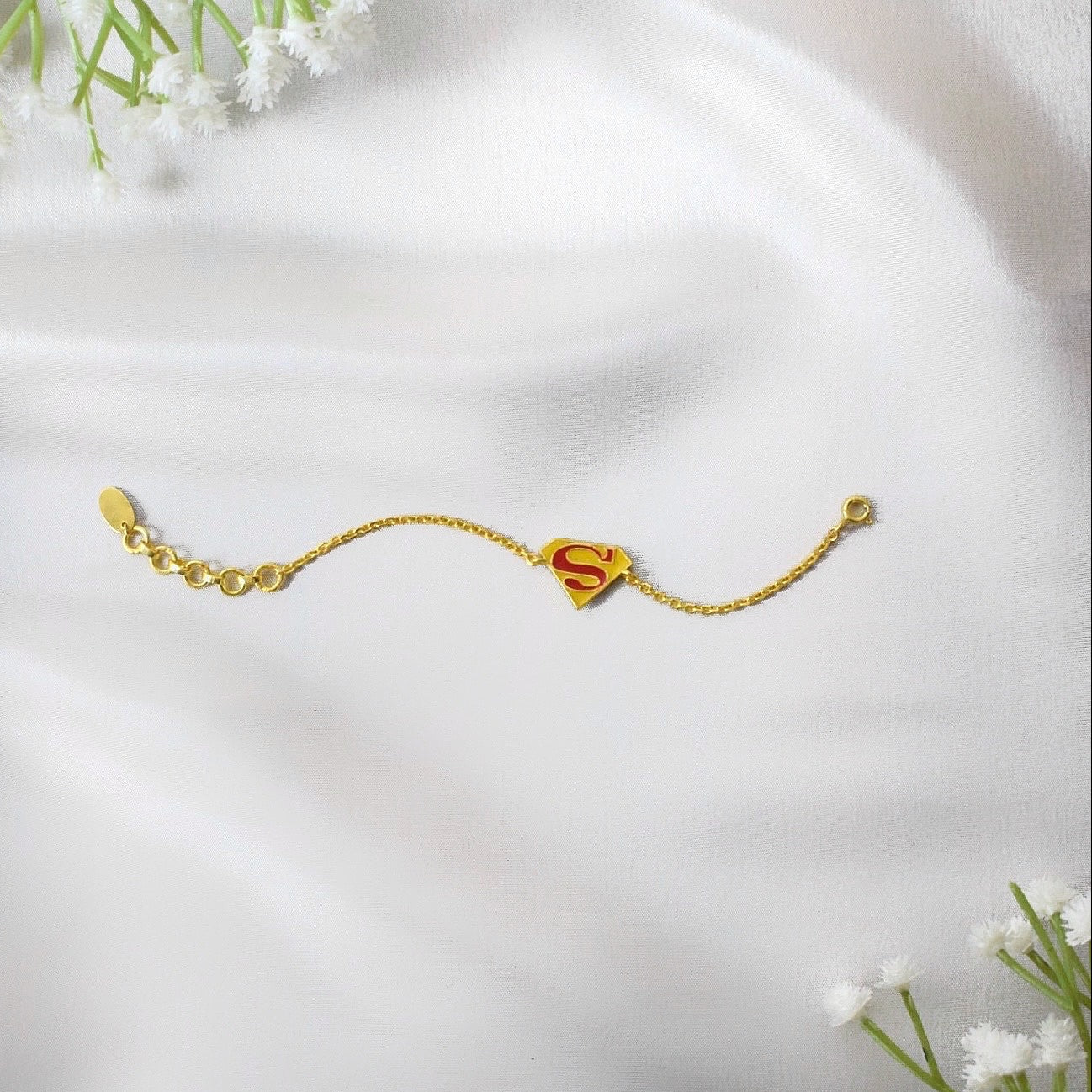 Gold bracelet with a red 'S' superman